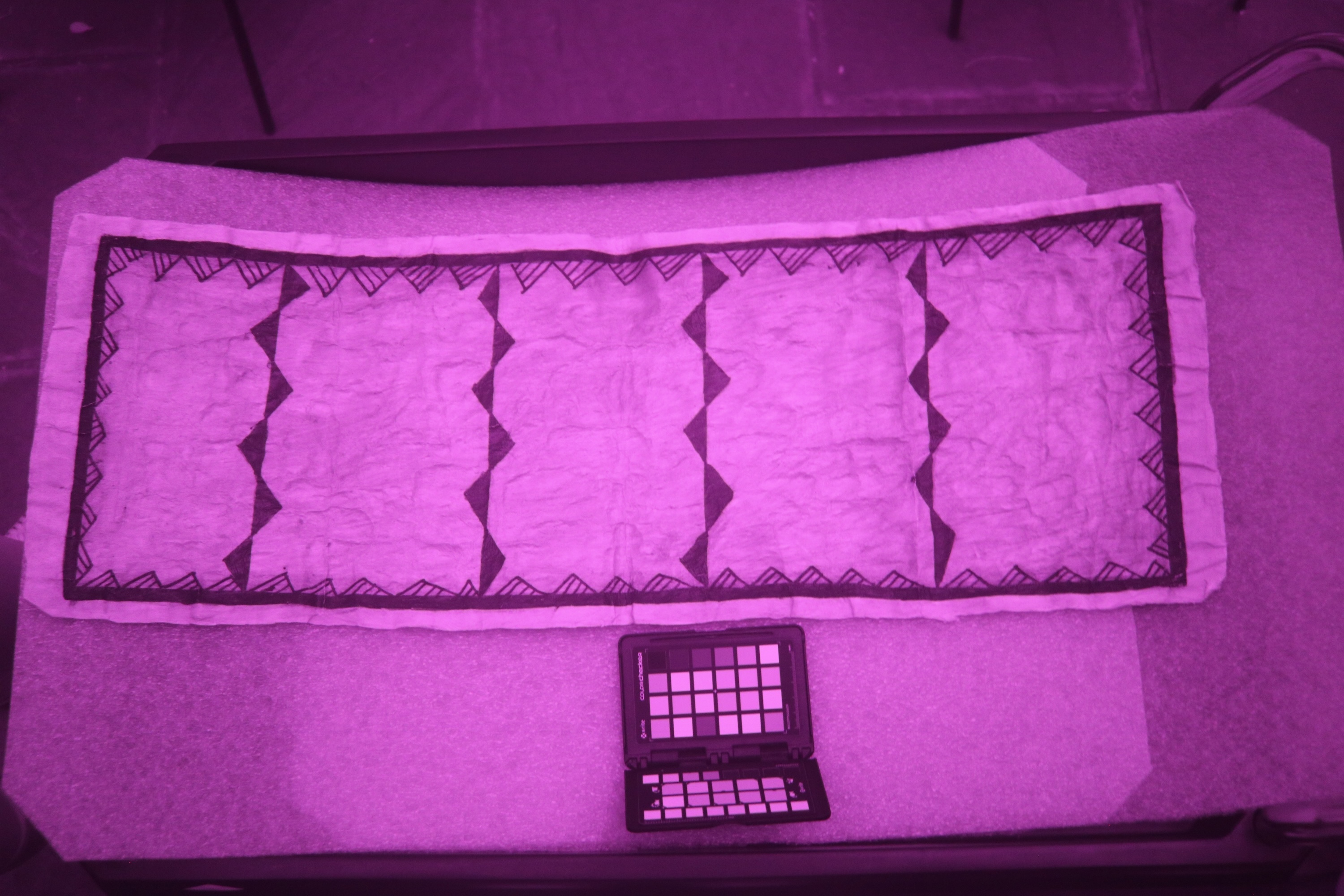 The solid black siapo from before, this time with the underlying geometric design revealed in a purple-tinted infrared photo.